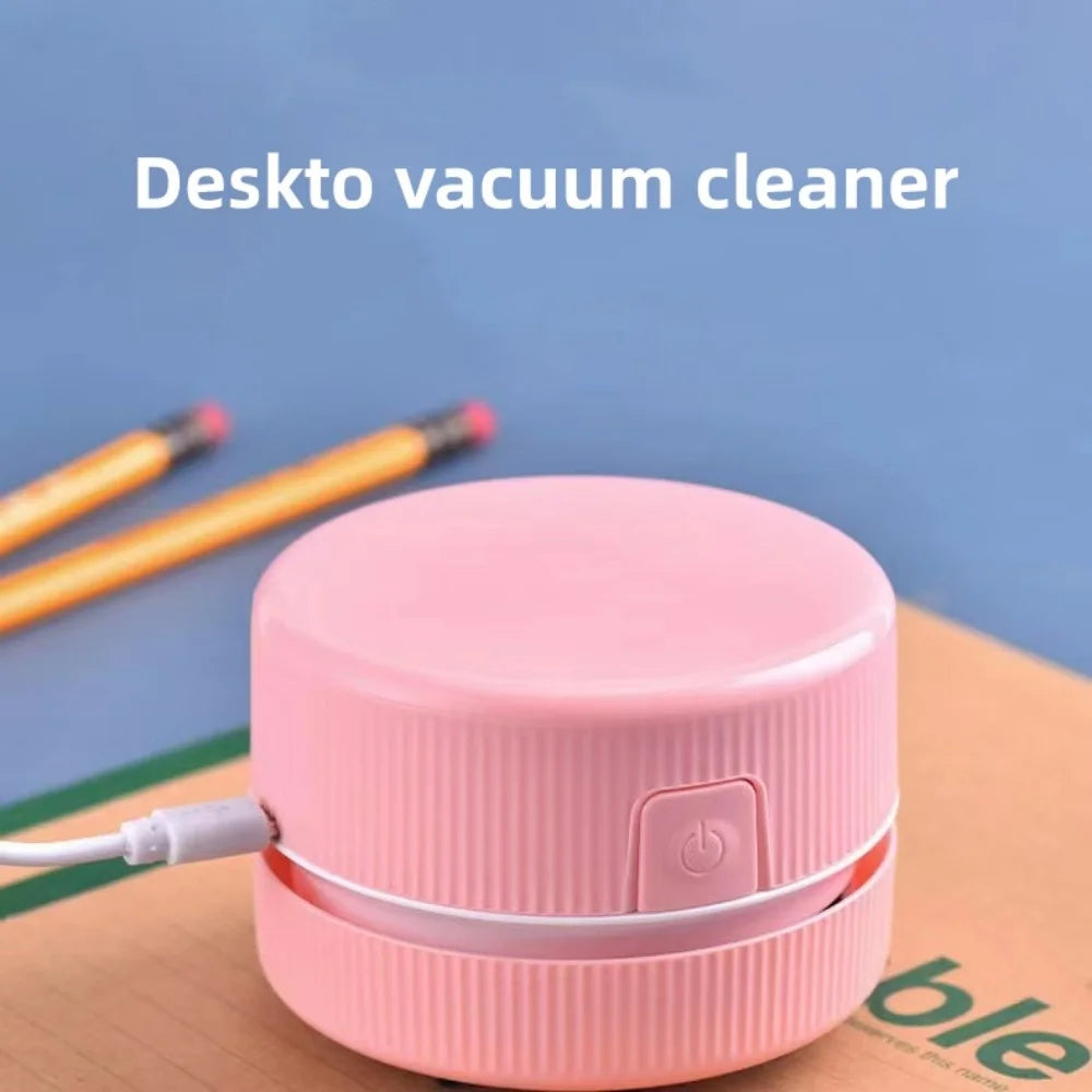 Eine rosa Mini-Desktop-Staubsauger neben einem gelben Stift auf einer Holzoberfläche.
