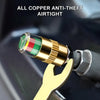 Close-up of a copper anti-theft tire pressure indicator valve cap with color coding, held by a gold-colored tool.