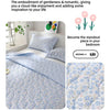 A light blue quilted blanket with a floral pattern is displayed on a bed, emphasizing a sweet and romantic theme.