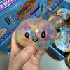 Eine Hand hält ein durchsichtiges, farbenfrohes Perlen-Dumpling-Squishy-Spielzeug in seiner Verpackung.