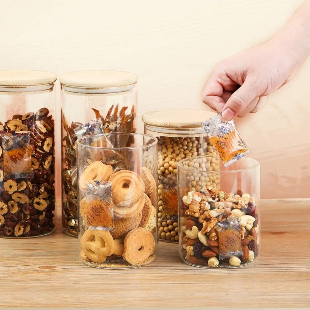 Various glass jars filled with dried ingredients and color-changing silica gel moisture absorber sachets