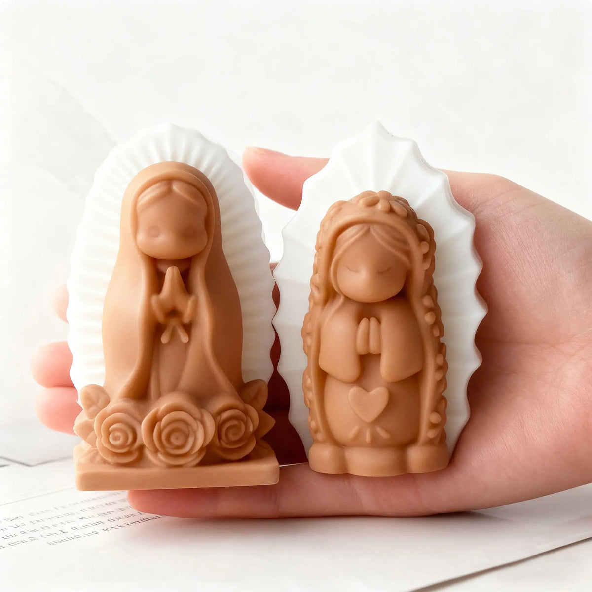 A hand holds two silicone molds shaped like praying girls, used for candles, soap, and craft decor.