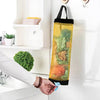 A hand is holding a yellow mesh plastic bag dispenser with a black strap, positioned next to a white cabinet.