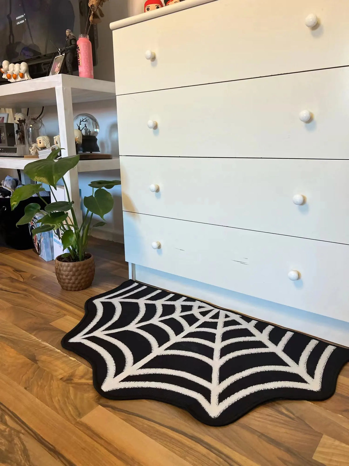 A black and white decorative rug featuring a spider web design with a ghost motif placed on a wooden floor.