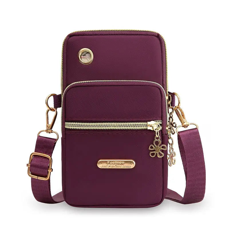 Bolso cruz impermeable de nylon morado oscuro con herrajes dorados y compartimento con cremallera.