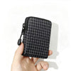 A hand holds a black compact EDC utility pouch featuring a fine grid pattern.