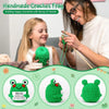 A woman is crocheting a frog toy for a child, surrounded by finished crochet frogs.