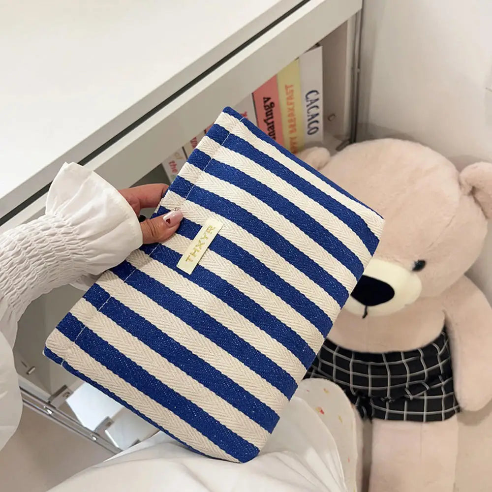 Pochette en crochet à rayures bleu marine et blanc posée sur une surface blanche à côté d'un grand jouet en peluche.