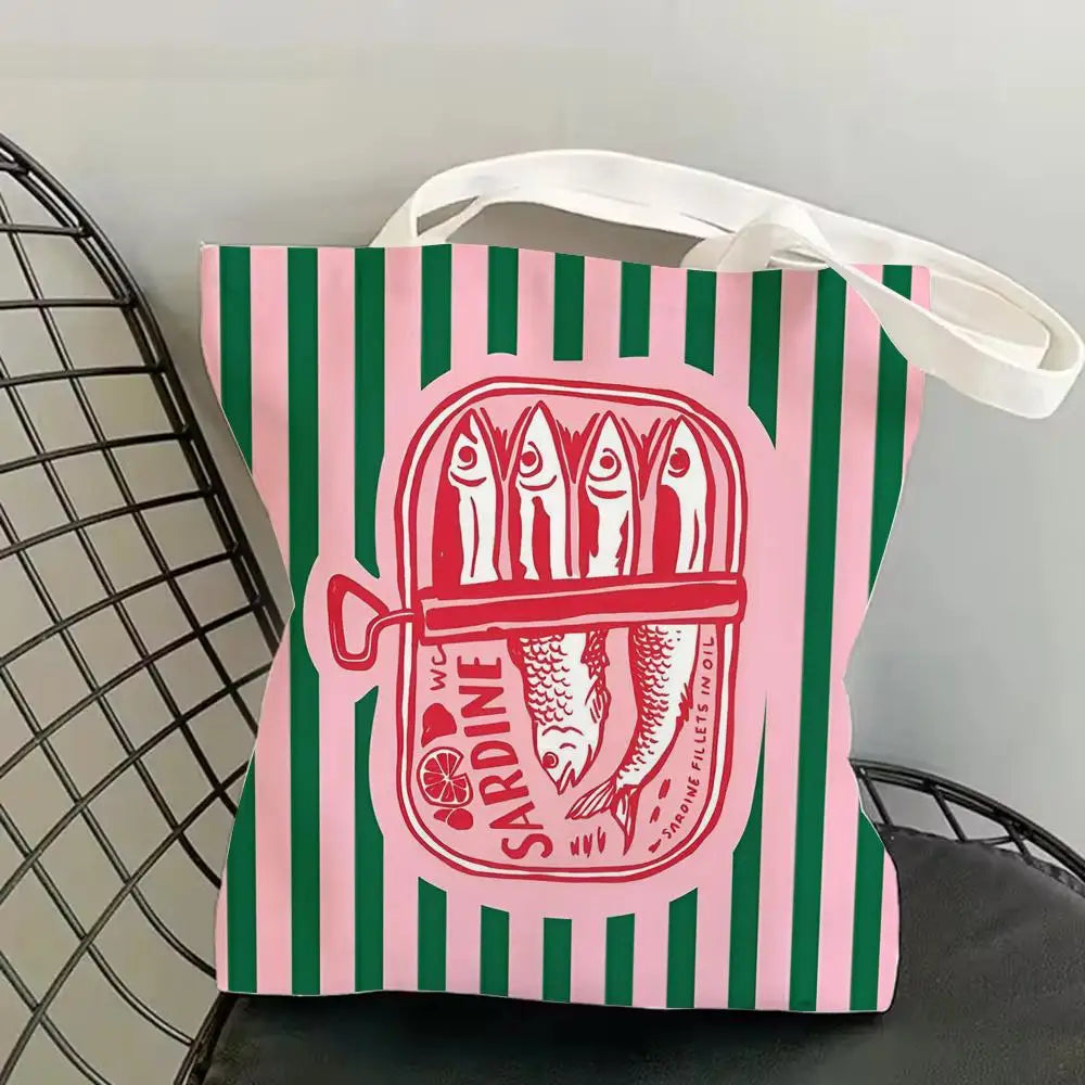 A pink and green striped tote bag featuring a red illustration of sardines.