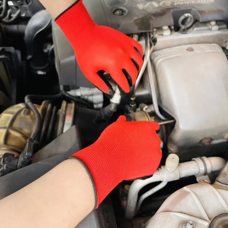 A hand wearing a red breathable PU-coated nylon work glove is working on an engine component.