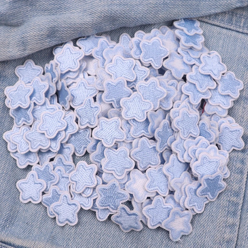 A collection of light blue and white embroidered star-shaped iron-on patches for DIY clothing decoration.