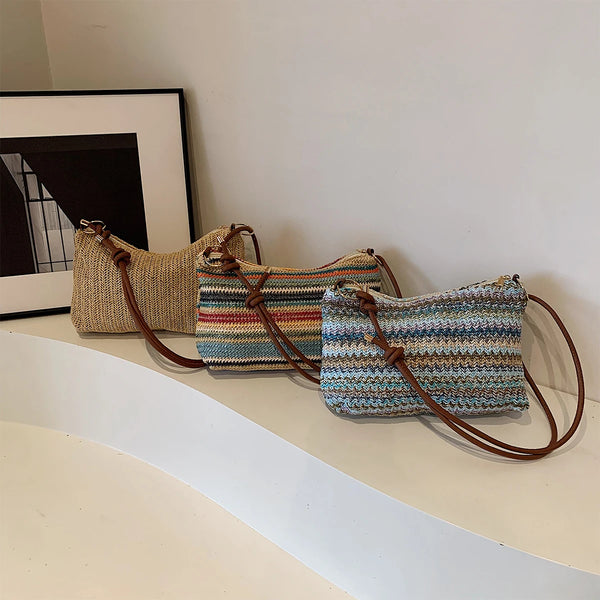 A close-up of a striped woven straw tote bag with brown leather straps resting on a white surface.