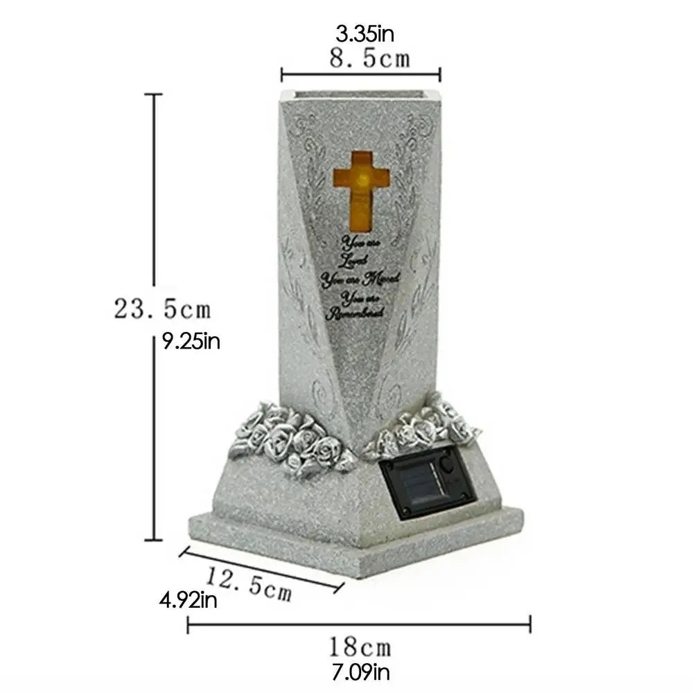 A gray solar-powered memorial vase featuring a cross and engraved text on a square base.