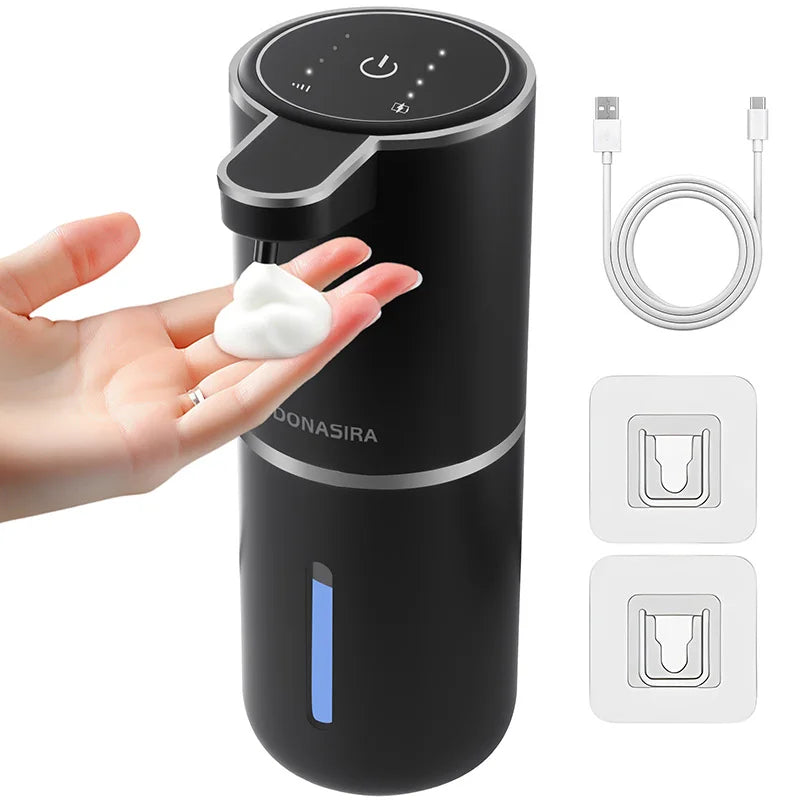 A black touchless automatic soap dispenser is shown with a hand dispensing soap, along with charging cables and replacement p