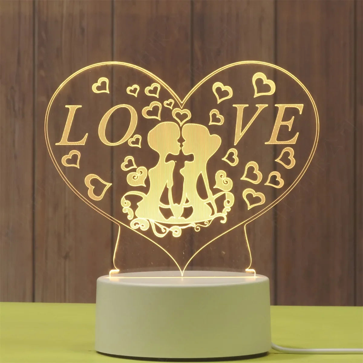 A glowing heart-shaped LED night light lamp featuring the word LOVE and a silhouette of two embracing figures.
