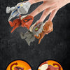 A hand is holding several mini finger dinosaur toys, including a green and gray dinosaur, an orange dinosaur, and a brown din