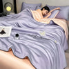 A person is lying on a purple comforter featuring silver embroidery of butterflies.