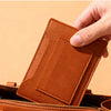 A close-up of a brown leather passport holder being placed into a handbag.