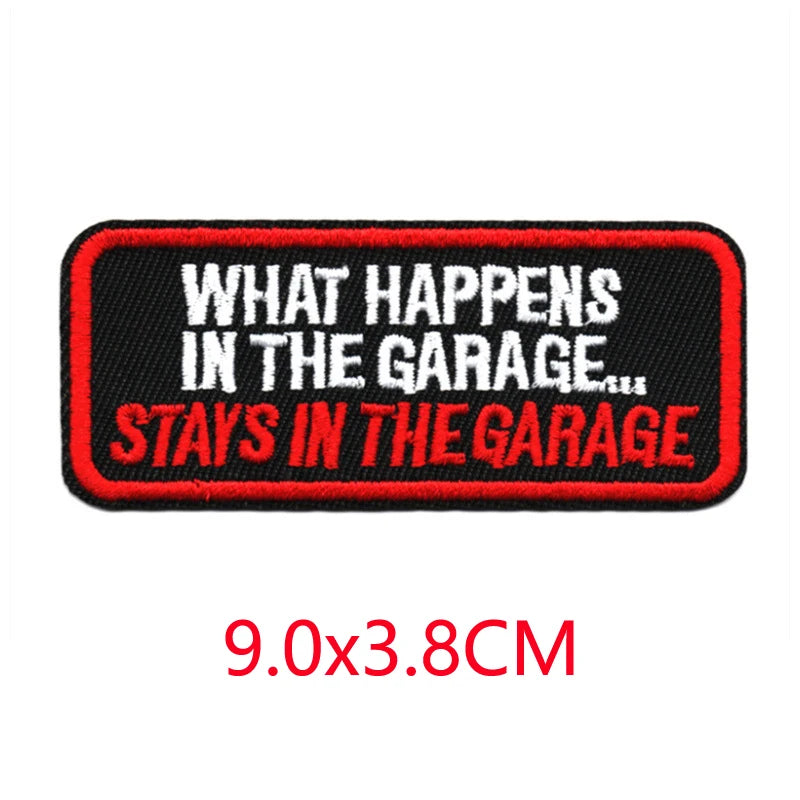 Black embroidered iron-on letter patch with red text that reads What Happens In The Garage Stays In The Garage