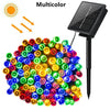 A cluster of multicolor LED string lights powered by a solar panel, ready for outdoor use.