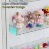 A clear acrylic wall-mounted display shelf holding several small, cute, pink and brown animal figurines.