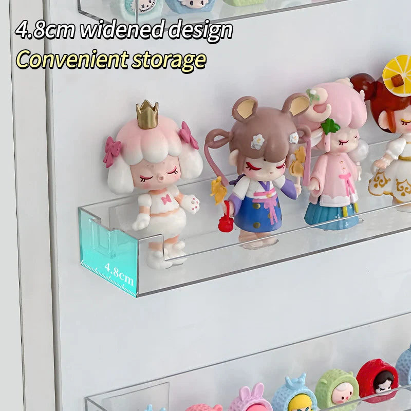 A clear acrylic wall-mounted display shelf holding several small, cute, pink and brown animal figurines.