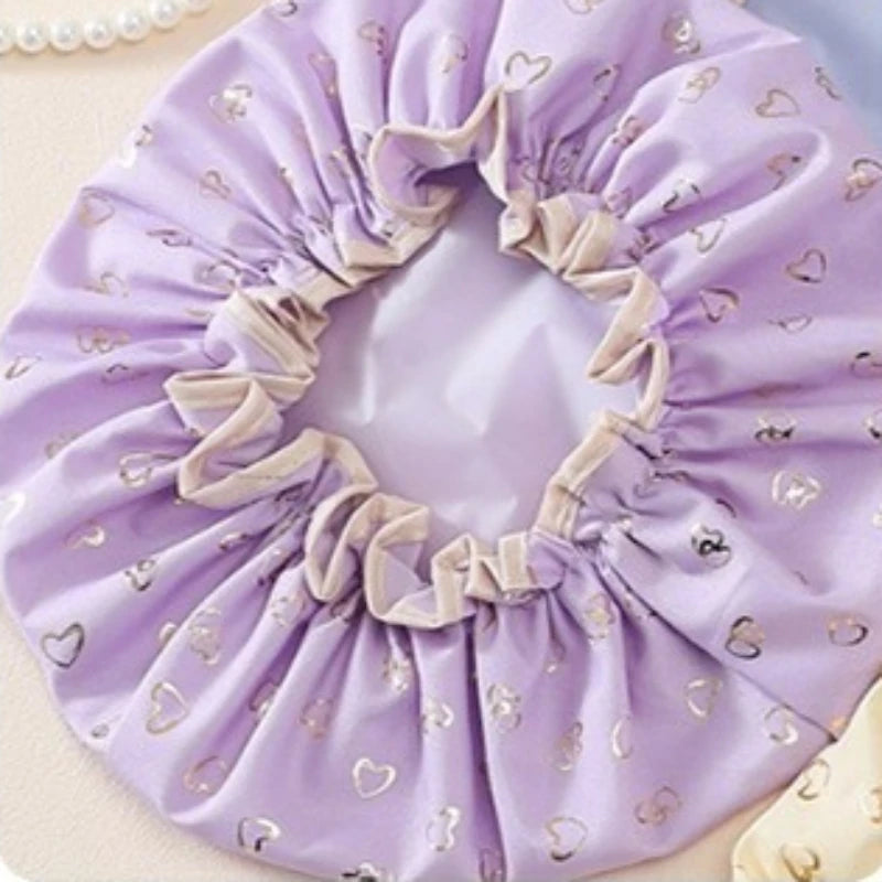 A lavender reusable elastic shower cap with a ruffled edge and small heart patterns.