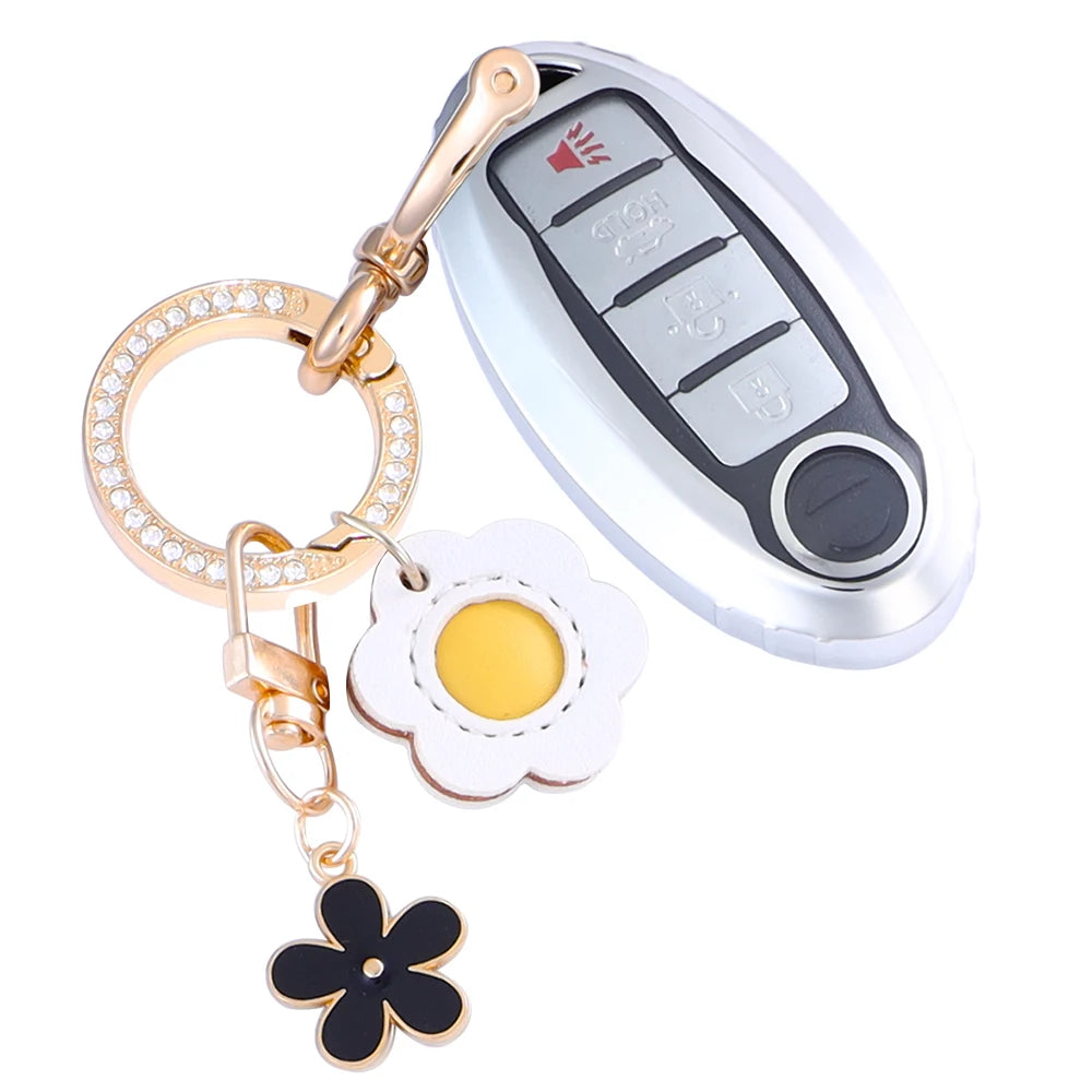 A silver silicone key fob cover with a gold chain and a flower charm attached.