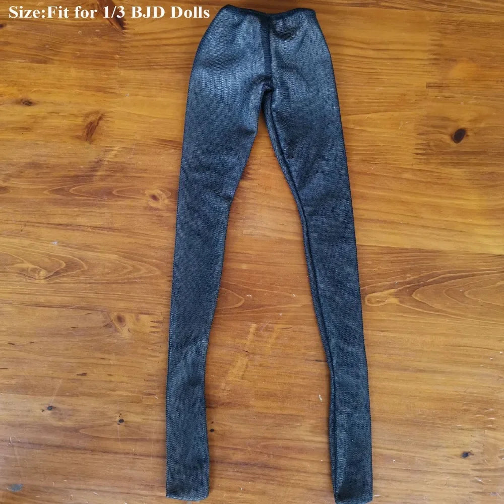 A pair of dark gray, sheer stockings or tights for a fashion doll, laid flat on a wooden surface.