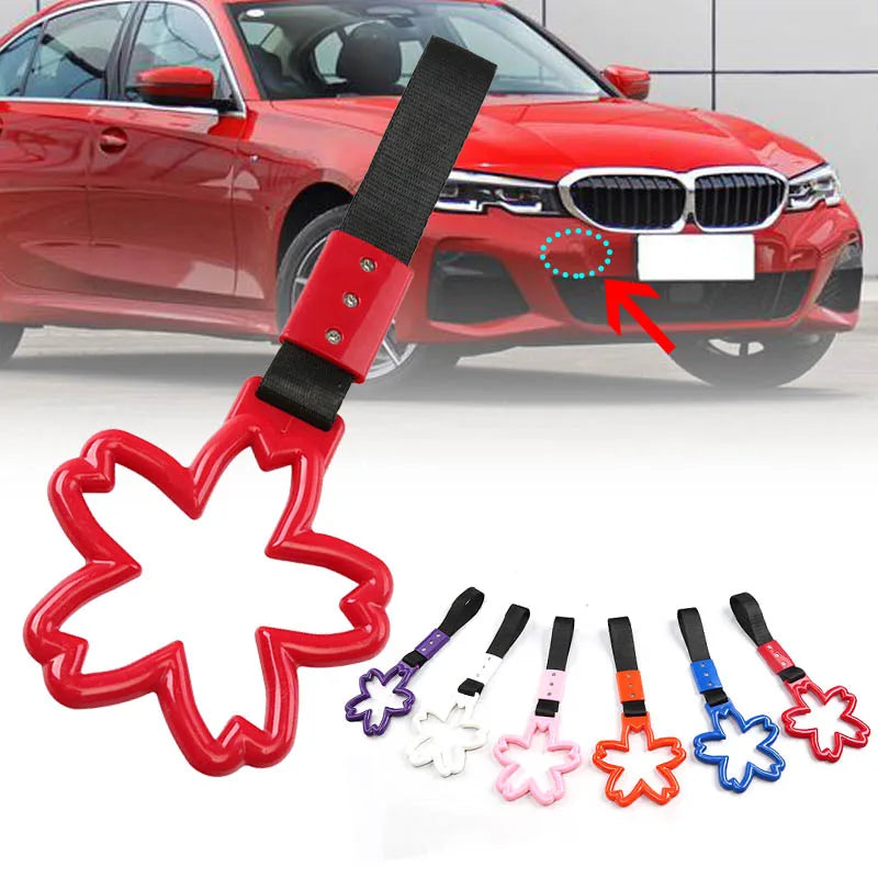 Red cherry blossom tow strap with steel hook shown attached to a BMW car grille.