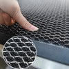 Close-up view of a black non-slip water-resistant doormat texture being touched by a finger.