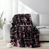 A pink and black retro skull and clown horror art throw blanket draped over a white sofa.