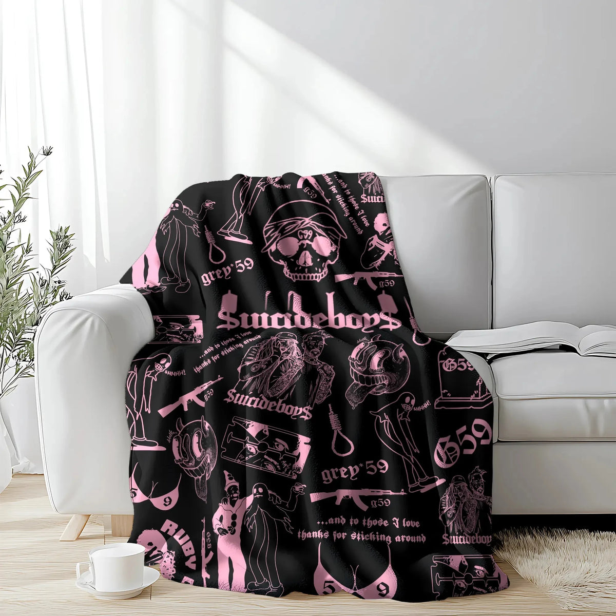 A pink and black retro skull and clown horror art throw blanket draped over a white sofa.