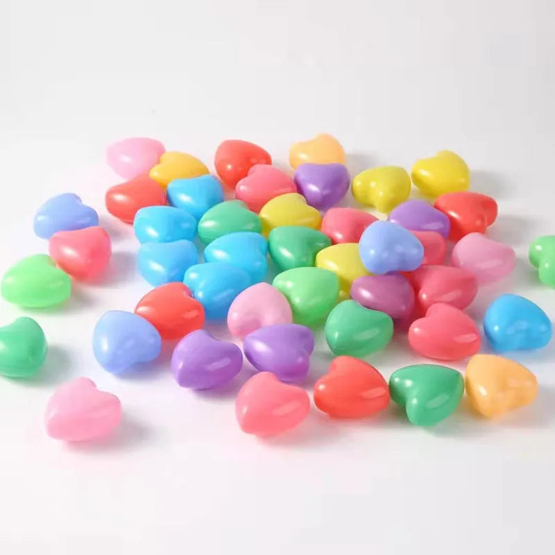 A pile of colorful, non-toxic ball pit balls in various shades of pink, purple, green, yellow, and blue.