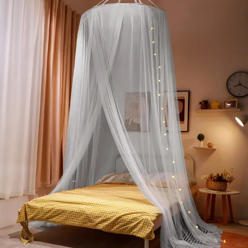 A romantic canopy mosquito net draped over a double bed with yellow bedding and sheer white fabric.