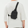 A black 2-in-1 convertible waist and crossbody sling bag worn on a white t-shirt.