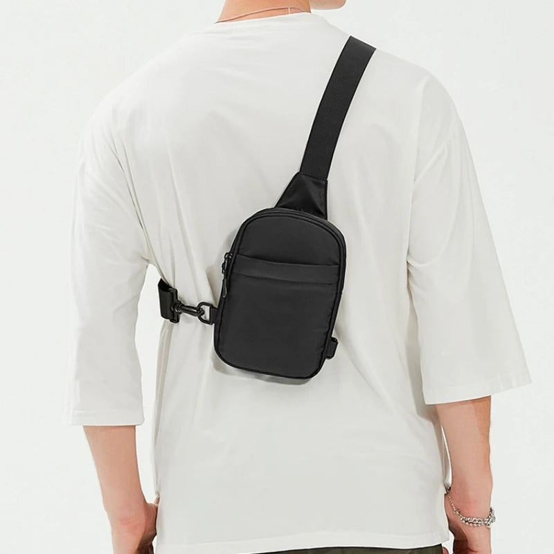 A black 2-in-1 convertible waist and crossbody sling bag worn on a white t-shirt.