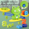 A green frog toy is shown balancing on a blue track, surrounded by other small frogs and number blocks.