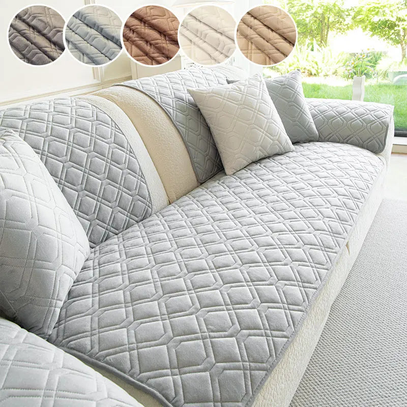 A light gray anti-slip sofa cover featuring a quilted geometric pattern and cream accent pillows.