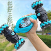 A hand holds a black and teal RC stunt car with grips, demonstrating the remote control vehicle.