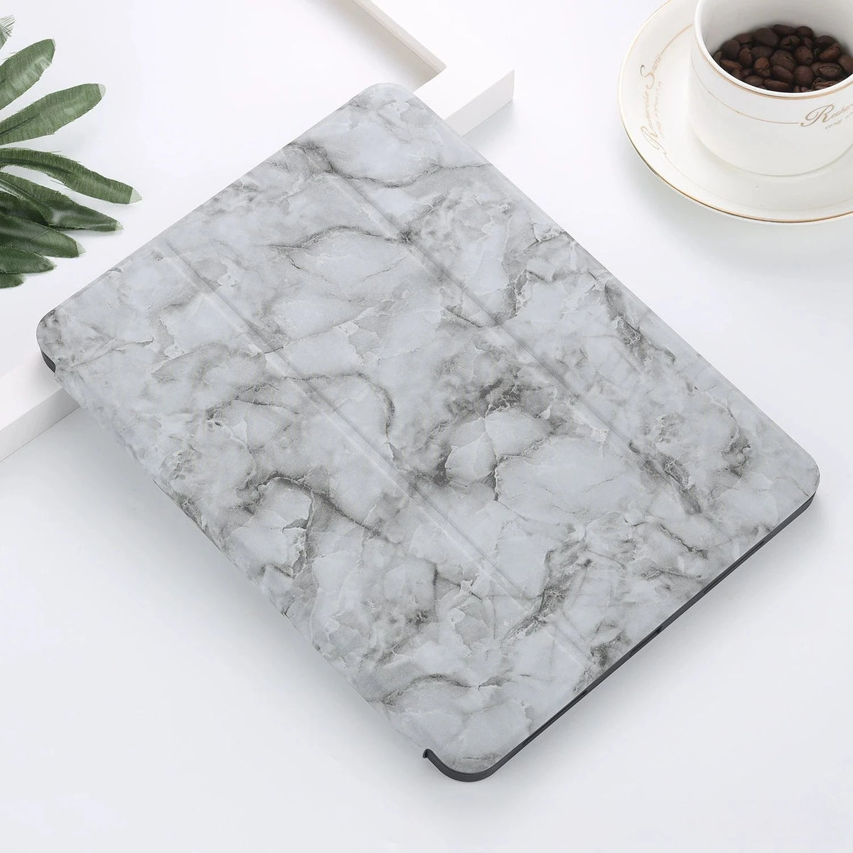 A gray marble patterned case for an iPad Pro with a built-in pencil holder placed on a white surface.