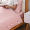 Pink anti-slip bedsheet quilt clips are visible on a pink bed, with a person reading nearby.