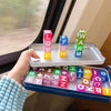 A hand holds a tray of colorful magnetic alphabet and number building blocks with various letters and numbers.