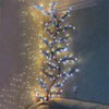 A vertical string of blue LED lights shaped like a cherry blossom tree illuminating a wall.