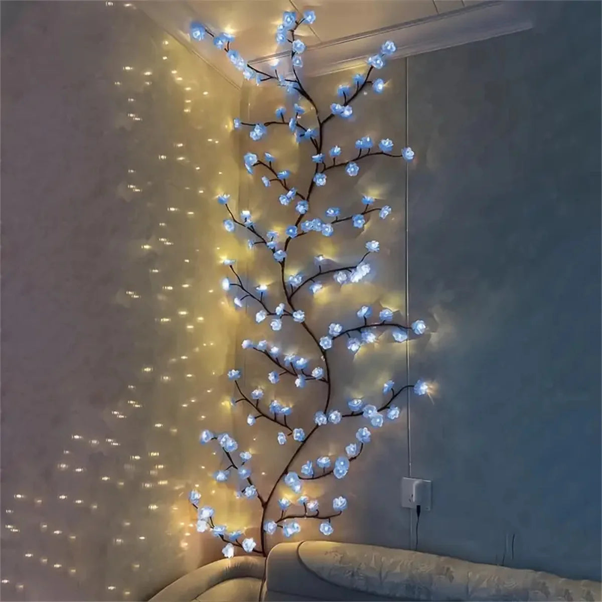 A vertical string of blue LED lights shaped like a cherry blossom tree illuminating a wall.