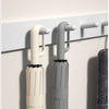 Two automatic folding umbrellas, one cream and one gray, are displayed hanging on a wall.