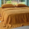 A mustard yellow pure linen bed sheet set with pillows on a bed.