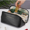 A hand is opening a black leather travel makeup organizer bag revealing a gold perfume bottle inside.