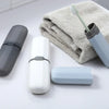 A white toothbrush travel case and a blue brush are shown next to a gray towel on a white surface.