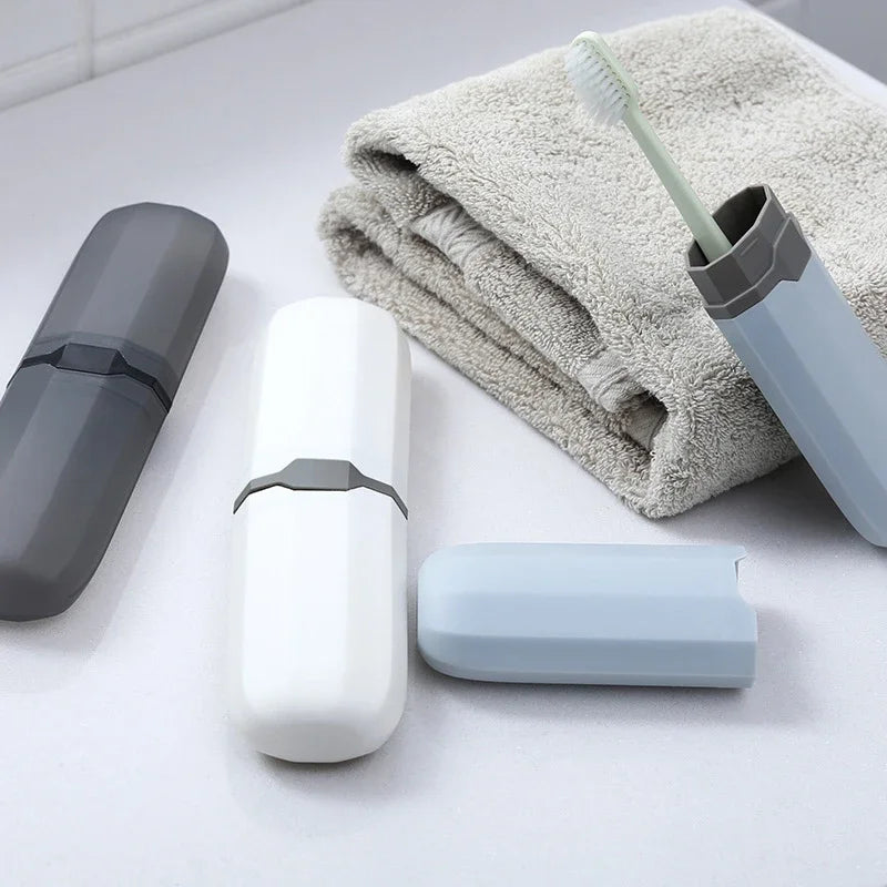 A white toothbrush travel case and a blue brush are shown next to a gray towel on a white surface.